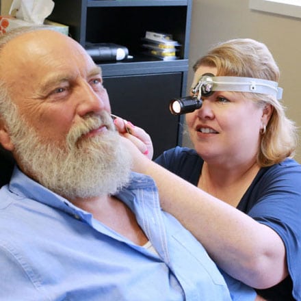 Audiologist Shannon M Christen examining a patient's ear with a headlamp