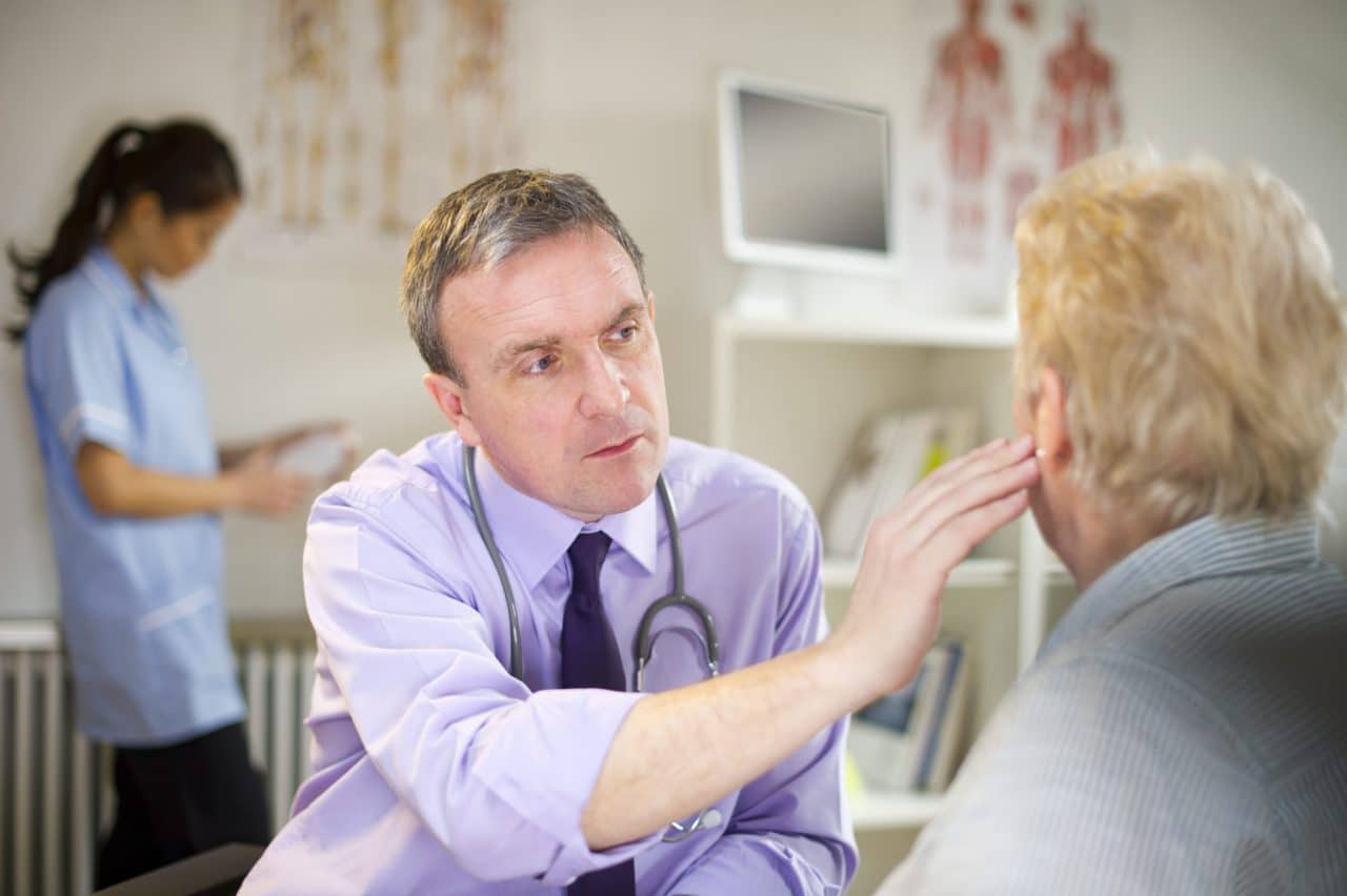 An audiologist examining a patient and touching their ear