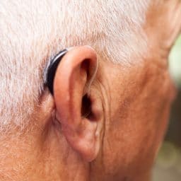 Man's ear with a very modern, low-profile and discrete hearing aid.