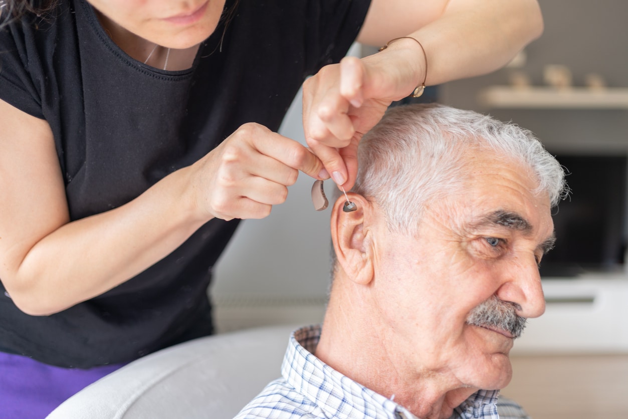 Close up of a senior man being fit for a hearing aid.