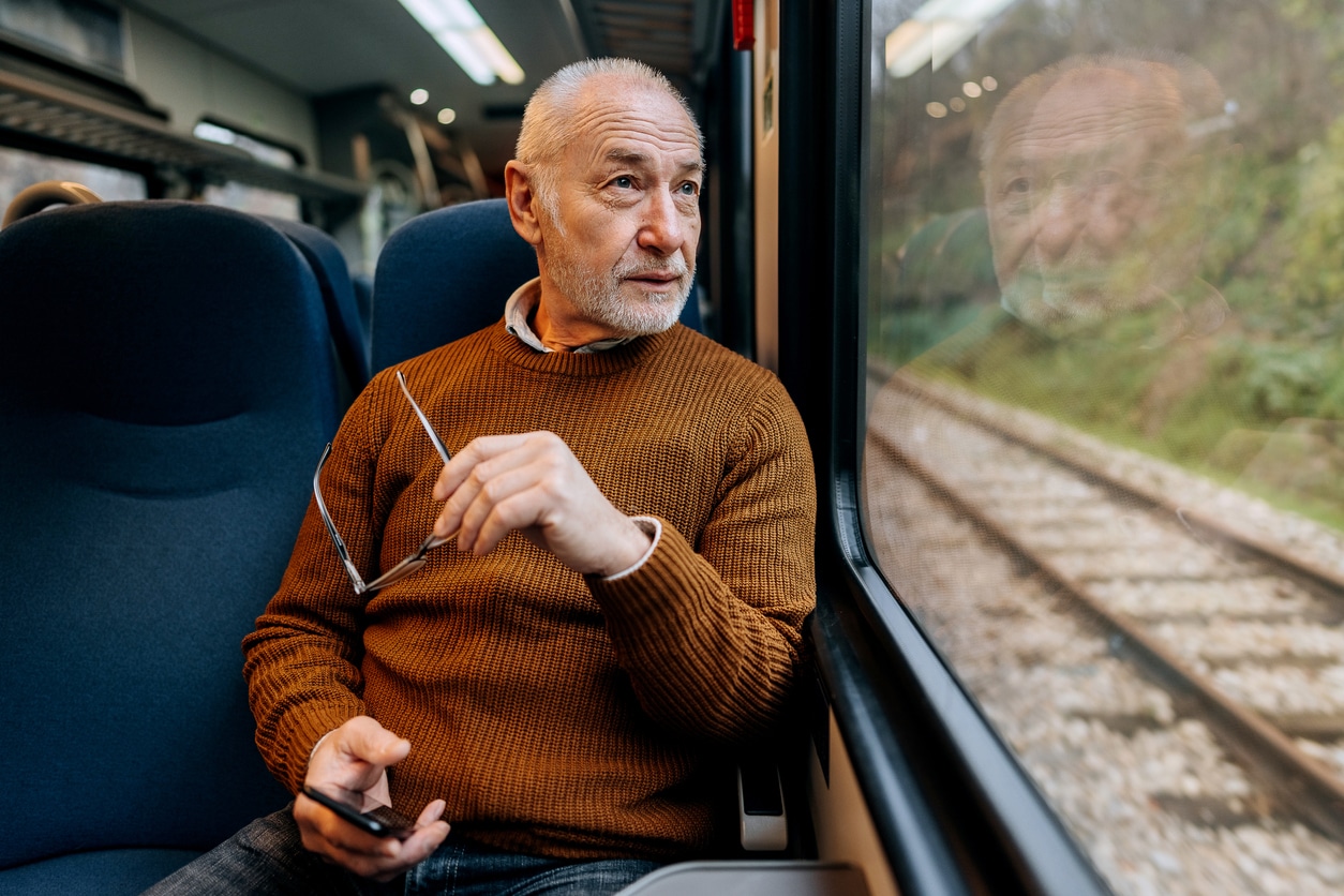 Senior man sitting on a train looking out the window