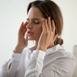 Woman with tinnitus rubbing her temples