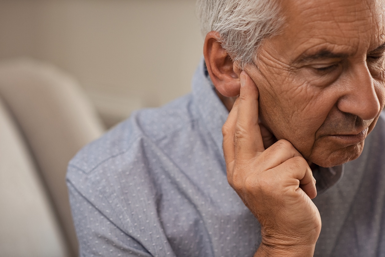 Senior man holds ear